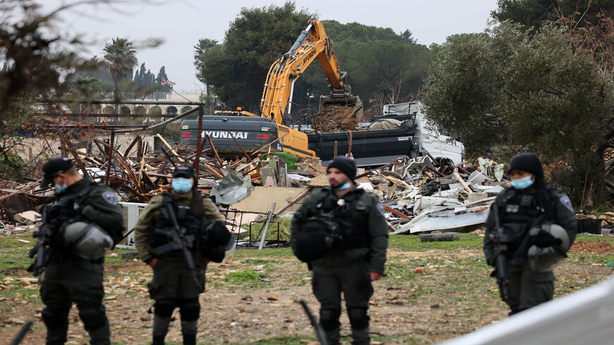 Israeli forces stand guard as machinery clean the ruins of the Palestinian Salhiya family's house, in the Sheikh Jarrah neighborhood, Jerusalem, Jan. 19, 2022.