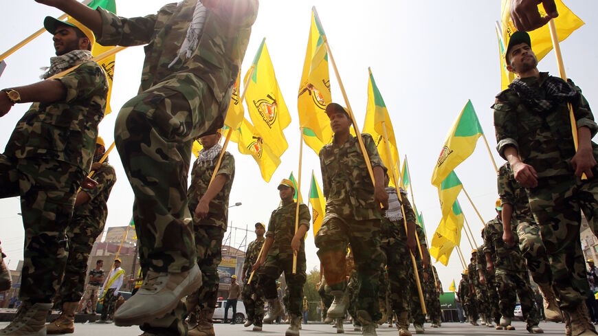 Shiite Muslim men in the military fatigues of Iraq's Kataib Hezbollah wave the party's yellow flags as they march through Baghdad during a parade marking Al-Quds (Jerusalem) International Day on July 25, 2014. 