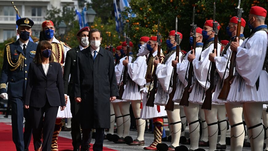 Greek President Katerina Sakellaropoulou (L) and her Israeli counterpart Isaac Herzog review the presidential guard during an official welcome ceremony at the Presidential Palace in Athens