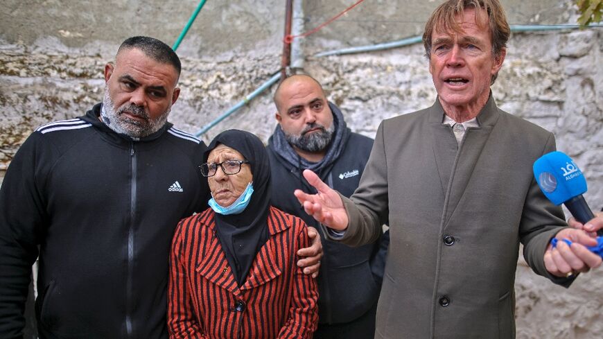 Fatima Salem (C) looks on as Sven Kuehn von Burgsdorff, head of the European Union's mission to the West Bank and Gaza Strip (R), speaks to the media during his visit to her home in the east Jerusalem neighbourhood of Sheikh Jarrah, December 20, 2021