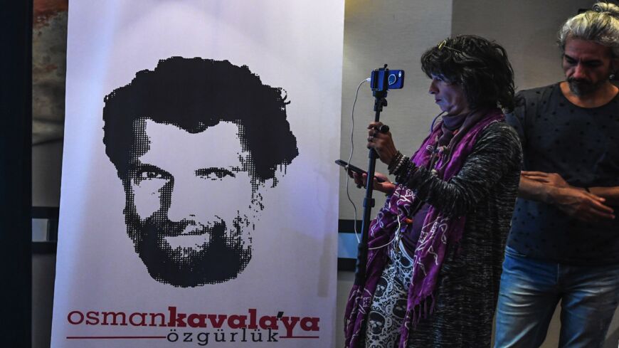 A journalist stands in front of a poster featuring jailed businessman and philanthropist Osman Kavala on Oct. 31, 2018.