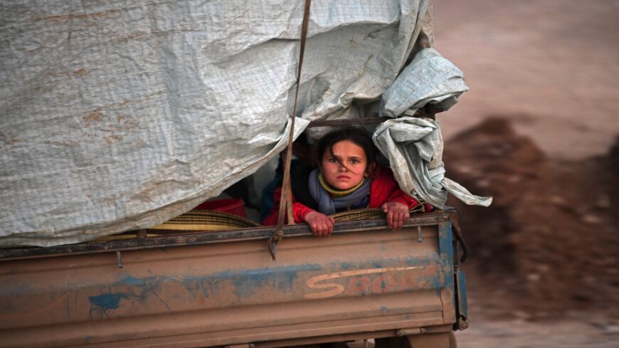 A displaced Syrian girl rides in the back of a truck on the way to Deir al-Ballut camp in Afrin's countryside on Feb. 19, 2020.
