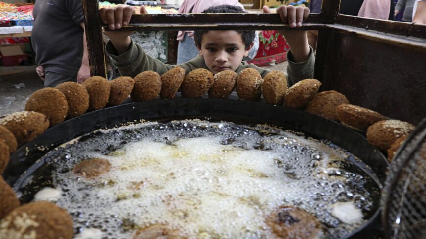 A Palestinian boy waits for falafel at a vendor in Hebron in the West Bank, April 18, 2021.