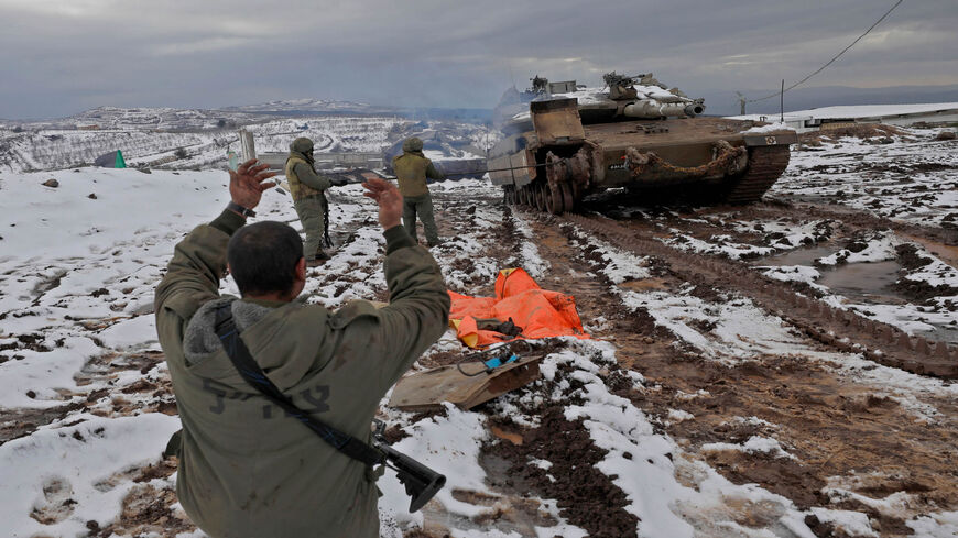 Israeli soldiers stand near a Merkava IV battle tank parked in a military post near the Syrian border in the Israeli-annexed Golan Heights, Jan. 24, 2022.