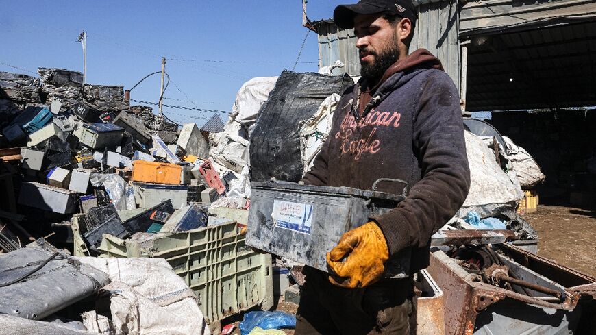 A Palestinian man picks discarded batteries to resell for recycling in the Gaza Strip; batteries are an essential power source in Gaza, where public electricity supply is sparse