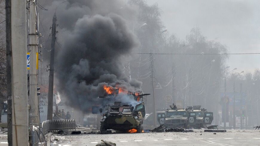 A Russian armoured personnel carrier burns next to an unidentified soldier's body in Kharkiv, Ukraine's second biggest city, following street battles