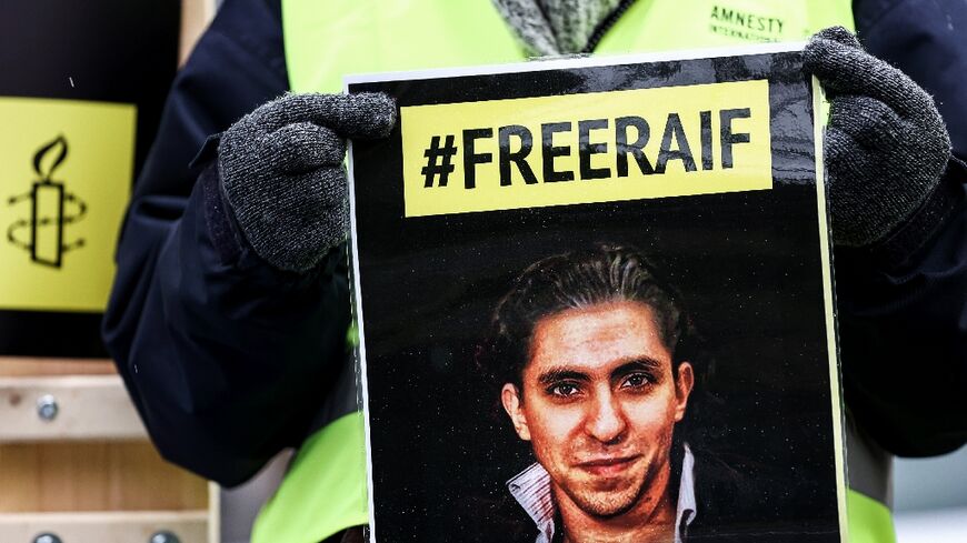 An Amnesty International activist holds a picture of jailed Saudi blogger Raif Badawi in front of the embassy of Saudi Arabia in Brussels on January 8, 2021, calling for his release