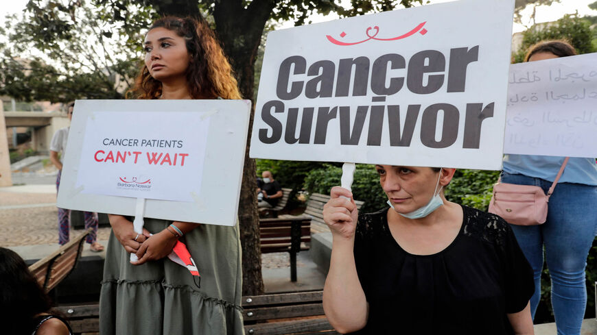 Demonstrators carry placards during a gathering by cancer patients to protest against the shortage of medicine that is threatening the treatment of tens of thousands of patients, outside the headquarters of the United Nations Economic and Social Commission for Western Asia, Beirut, Lebanon, Aug. 26, 2021.