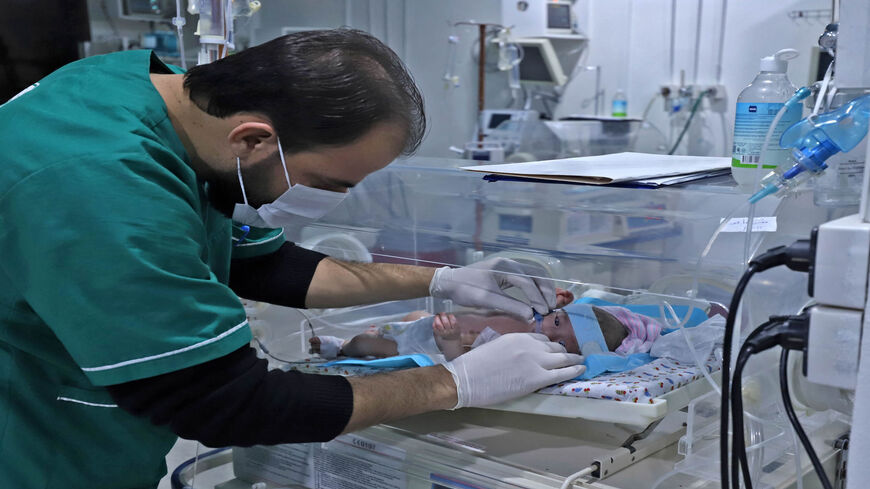 A physician treats a premature born baby lying in an incubator at the neonatal intensive care unit at Ibn Sina (Avicenna) Hospital that is part of the Syrian American Medical Society, Idlib, Syria, Feb. 1, 2022.