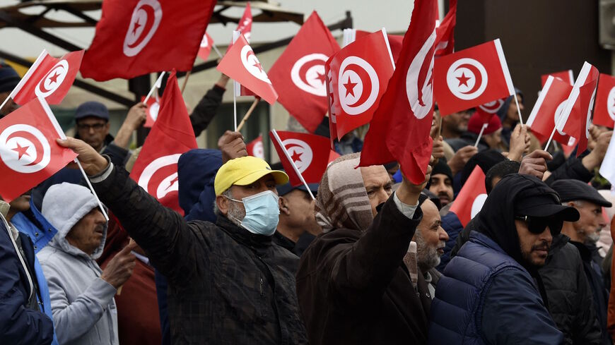 Tunisian protesters raise placards and national flags during a demonstration against their president, not far from the Tunisian Assembly (parliament) headquarters, in the capital Tunis, on March 20, 2022. 