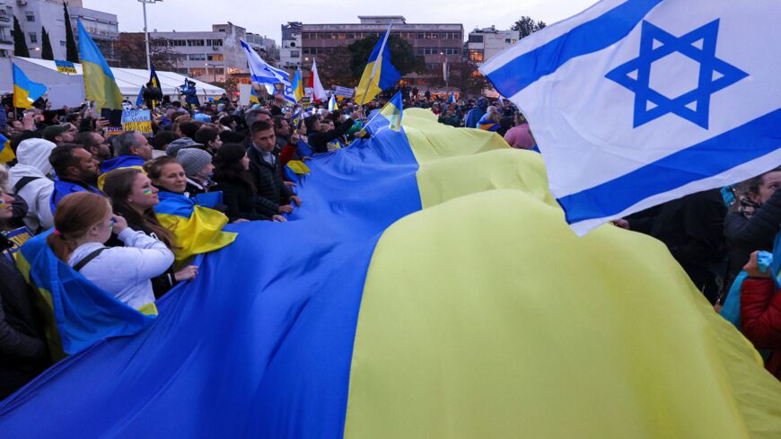 Demonstrators wave a giant flag of Ukraine and Israel .
