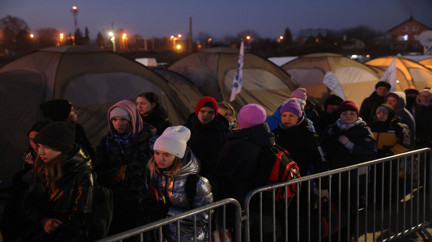 People who have just crossed from war-torn Ukraine into Poland wait to board buses provided by Polish authorities at the Medyka border crossing, Medyka, Poland, March 11, 2022.