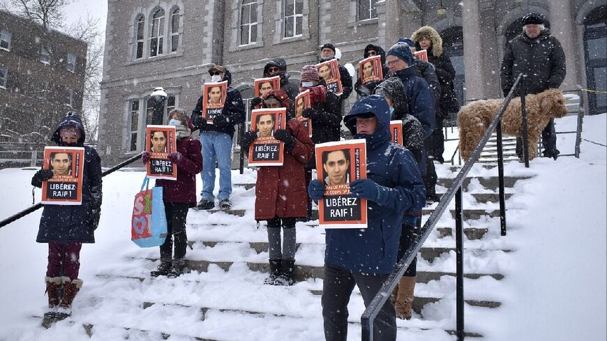Saudi blogger Raif Badawi, seen on pictures held by supporters at a February 2022 vigil in Montreal, has been released after serving a 10-year sentence in Saudi Arabia