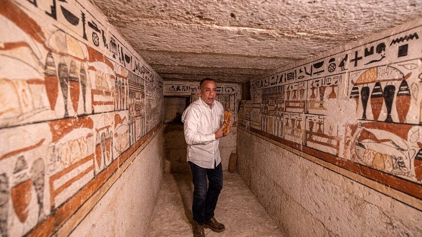 Mostafa Waziri, the head of Egypt's Supreme Council of Antiquities, holds a small statuette on March 19, 2022, inside one of the five ancient Pharaonic tombs recently discovered at the Saqqara archaeological site, south of the  capital Cairo