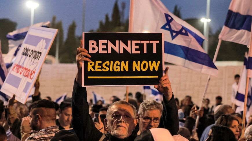 A man holds up a sign reading in English "[Israeli Prime Minister Naftali] Bennett resign now" during an anti-government protest by Israeli right-wing supporters in Jerusalem