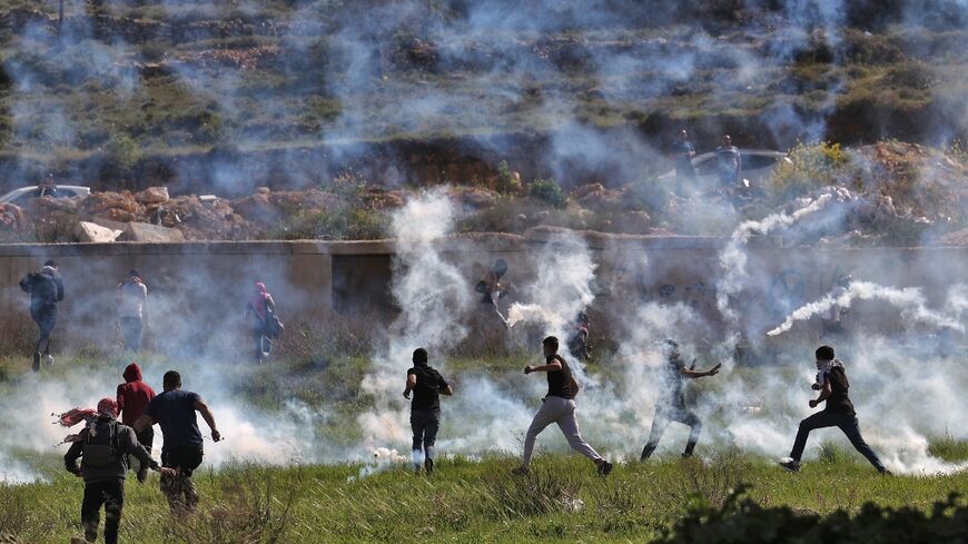 Palestinians run for cover during clashes with Israeli security forces at the northern entrance of Ramallah, near the Israeli settlement of Beit Eil, in the occupied West Bank, on April 11, 2022