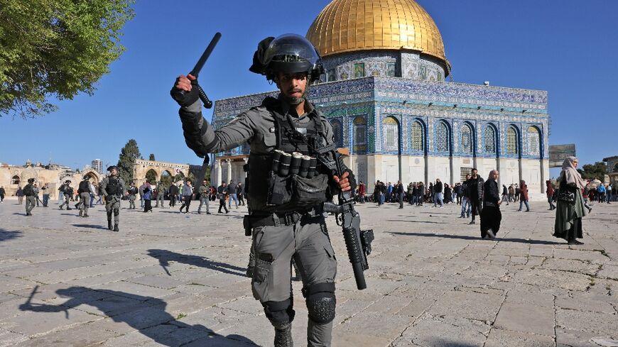 A member of the Israeli security forces lifts his batton in front of the Dome of the Rock mosque during clashes at Jerusalem's Al-Aqsa mosque compound, on April 15, 2022