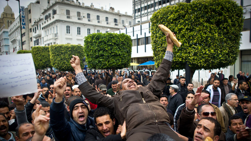 Tunisian man holding a baguette is carried by fellow protesters during a demonstration in Tunis on Jan. 18, 2011. 