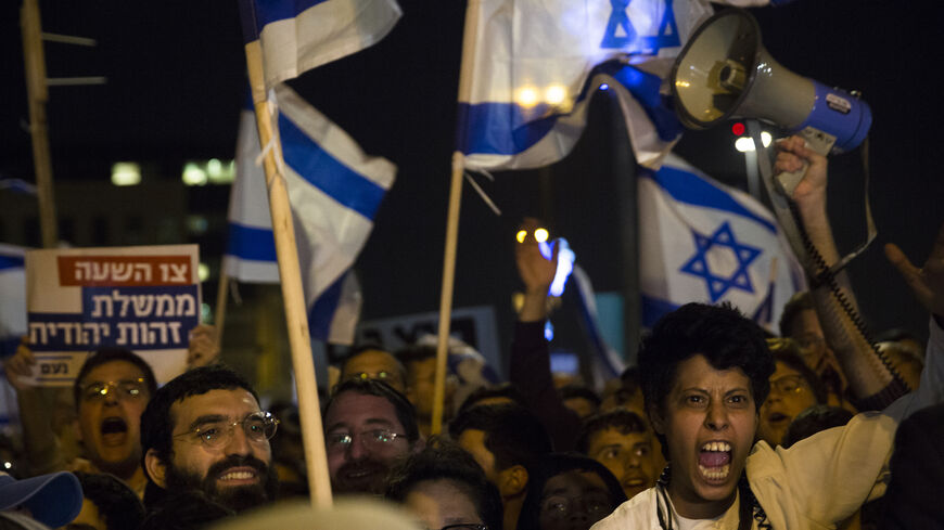 Right-wing Israeli supporters hold signs and flags as they protest against the Israeli government on April 6, 2022, in Jerusalem.