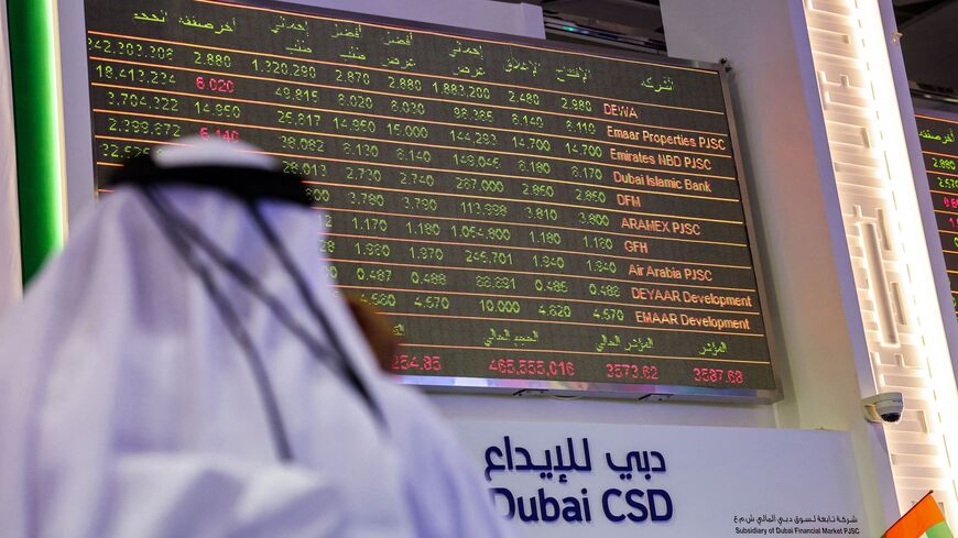 A man watches stock movements on a display at the Dubai Financial Market stock exchange in the Gulf emirate on April 12, 2022.
