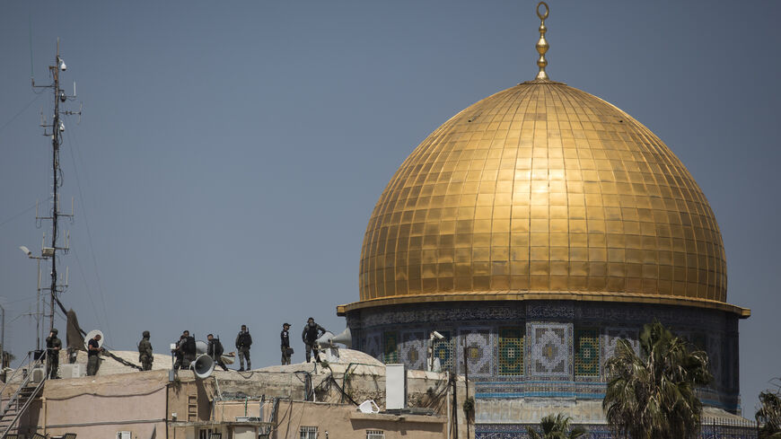 Israeli police officers stand on a rooftop near Al-Aqsa Mosque following clashes with Muslim prayers.