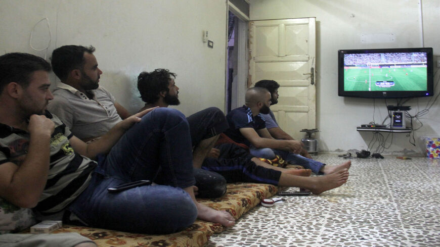 Syrian men watch the FIFA World Cup 2018 qualification soccer game between Iran and Syria, played in Tehran, in the rebel-held town of Binnish on the outskirts of Idlib, Syria, Sept. 5, 2017.