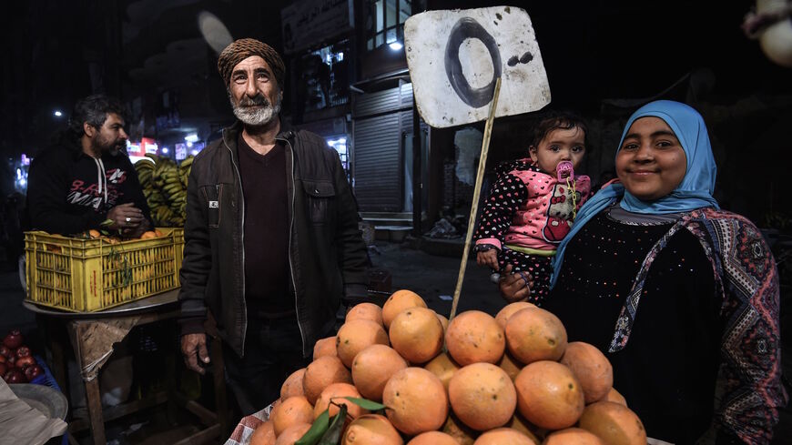 Egyptians smile for a photo as they buy fruits from a street vendor at a market in the Menufiya province north of Cairo on Feb. 22, 2018.  