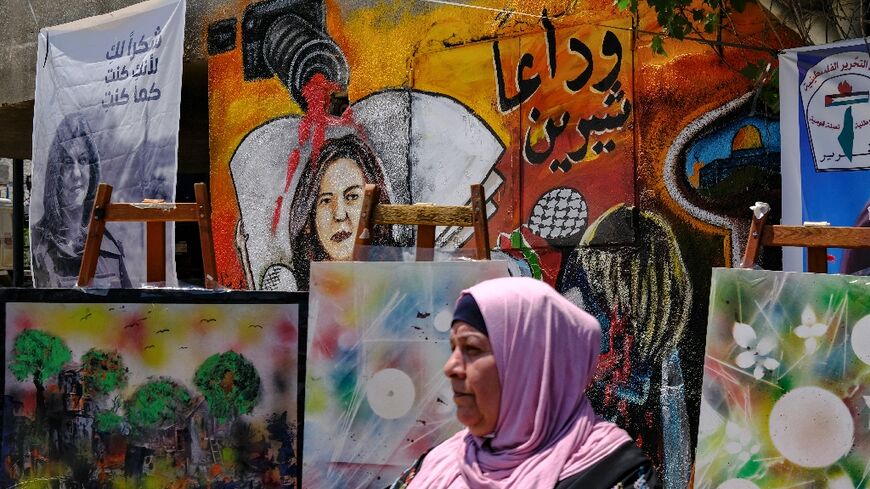 A woman stands in front of a mural, part of an art exhibit honouring slain Palestinian Al-Jazeera journalist Shireen Abu Akleh, at the spot where she was killed while covering an Israeli army raid in Jenin in the occupied West Bank