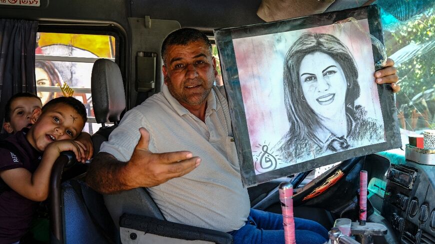 A van driver holds a portrait of Palestinian-American Al Jazeera journalist Shireen Abu Akleh as he passes the spot where she was killed while covering clashes in Jenin in the occupied West Bank