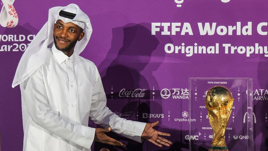 A man poses for a photo next to the FIFA World Cup Trophy while on display at the Katara cultural village in Qatar's capital Doha on Tuesday