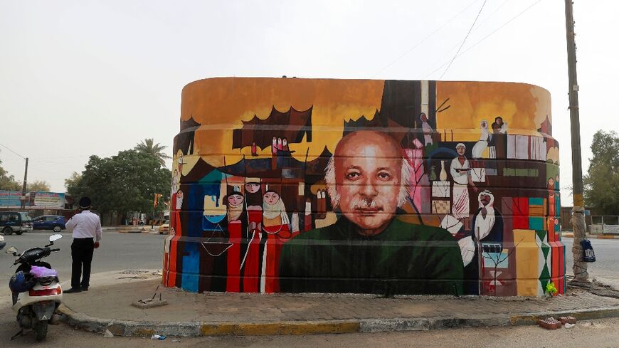 A policeman talks on the phone near a mural depicting Iraqi poet Muzzafar al-Nawab in Baghdad