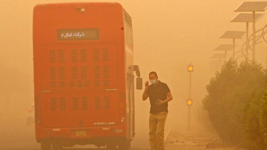 A commuter in Kuwait City waits to cross a street amid heavy sandstorms that have engulfed the Middle East
