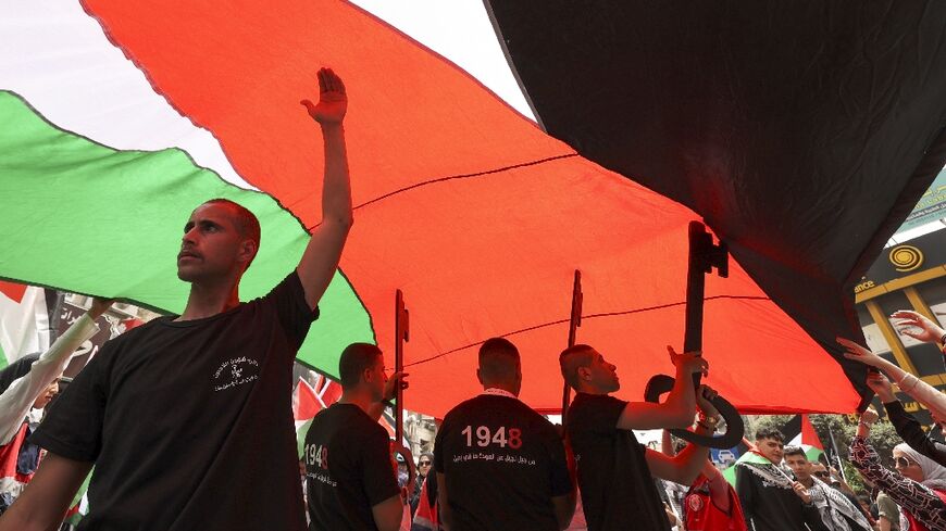 Palestinians march under a huge flag in the occupied West Bank city of Ramallah to mark the "Nakba", or catastrophe of Israel's creation 74 years ago