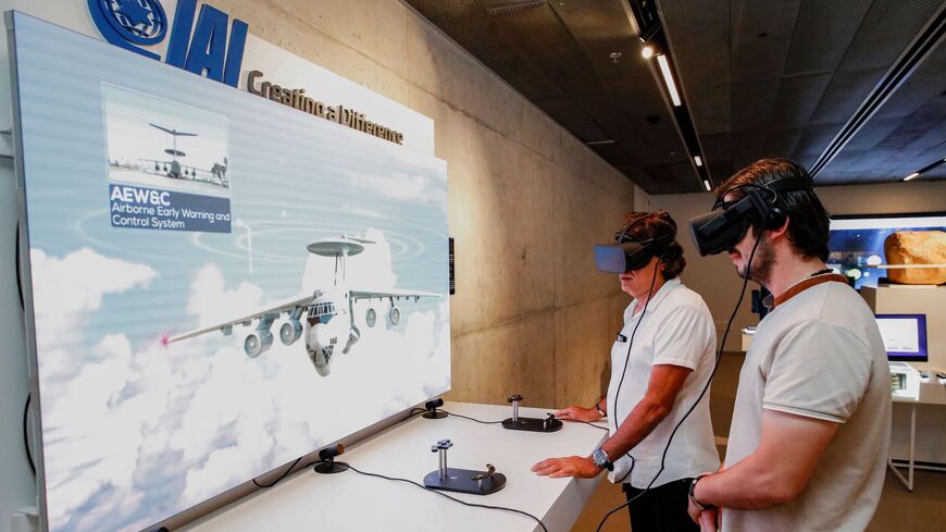 Visitors wearing virtual reality headsets interact with a display by the Israel Aerospace Industries.