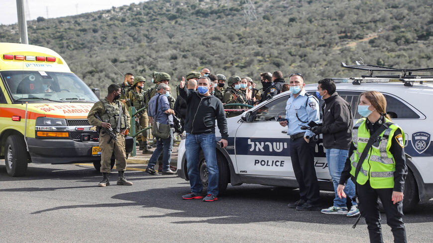 Israeli soldiers and policemen gather at the scene by the body of a Palestinian man who was shot dead reportedly while attempting a knife attack at the Gitai Avisar Junction, west of the Jewish settlement of Ariel and south of Nablus, West Bank, Jan. 26, 2021.