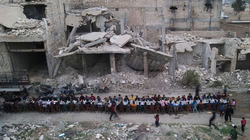 An aerial view shows Syrians sitting amidst the damaged buildings to break fast during an iftar gathering in Tadef.