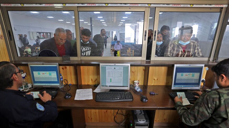 Palestinian officers check documents of workers waiting to reach Israel through the Erez crossing.