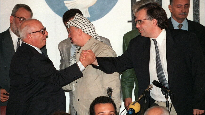 Palestinian Chief negotiator Ahmed Qorei Abu Ala (l) shakes hands with his Israeli counterpart Uri Savir (r) at the Taba hotel on the Egyptian shore of the Red Sea after signing the historical Taba agreement to extend Palestinian autonomy in the West Bank. Yasser Arafat, chairman of Palestine Liberation Organization (PLO) is in the center. Sept. 24, 1995. 