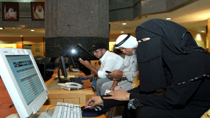 An Emirati female trader watches a quotation board from a computer screen at the Abu Dhabi stock exchange, June 7, 2006.