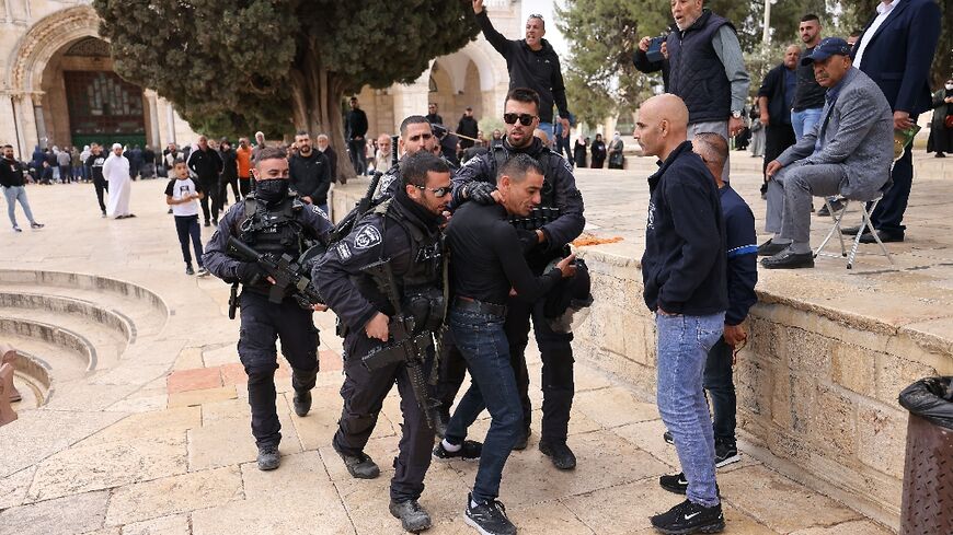 Israeli police restrain a Palestinian protester as security forces accompany a group of Jewish visitors past the Dome of the Rock at the Al-Aqsa mosque compound in the Old City of Jerusalem on May 5, 2022