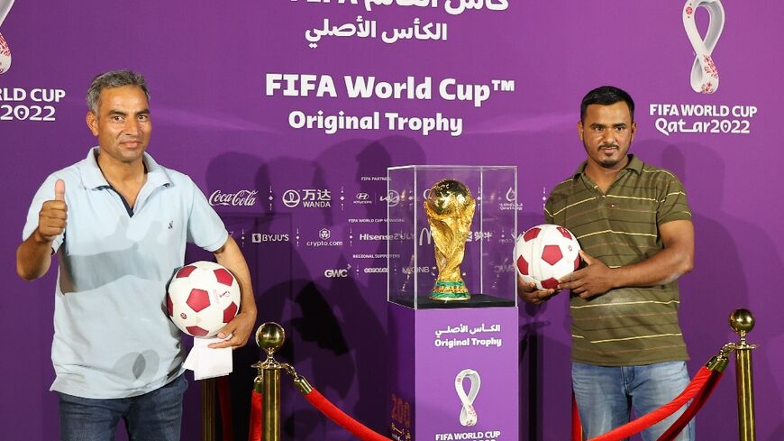 Foreigners pose next to the World Cup trophy in Doha for an event marking 200 days until the 2022 tournament 