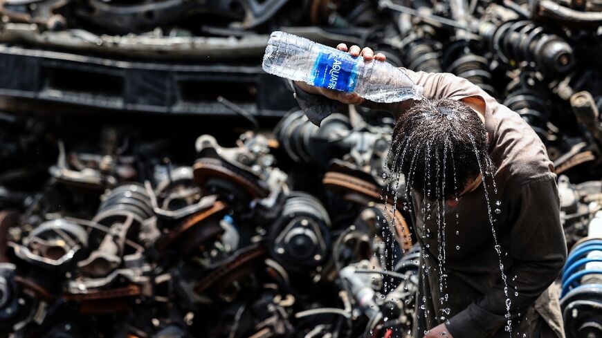 A migrant labourer at a used car parts lot in the UAE emirate of Sharjah tries desperately to cool down amid the sweltering heat