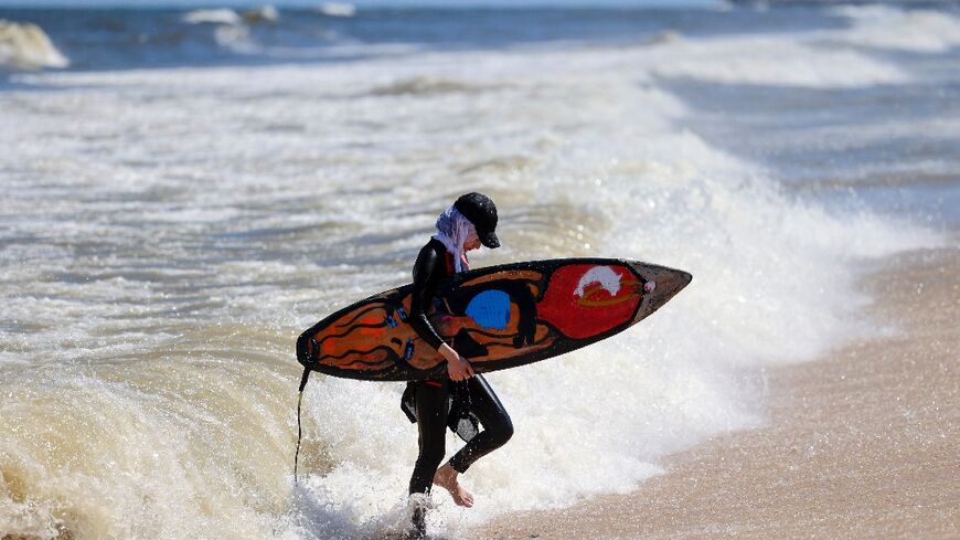 Palestinian surfer Sabah Abu Ghanem emerges from the water at a beach in Gaza City