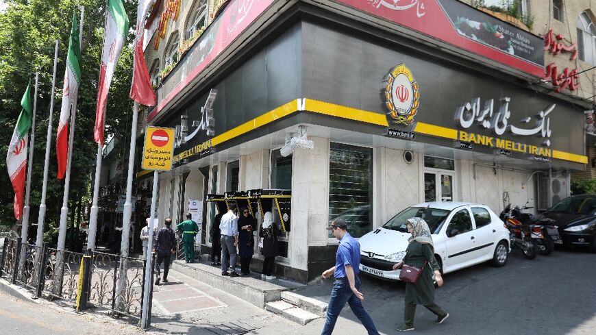 People pass a Bank Melli branch in the Iranian capital Tehran on May 20, 2019 