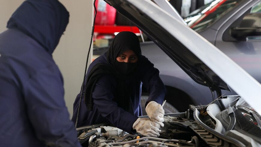 Ghada Ahmed (R) works on a car in Saudi Arabia, where garages are tapping women as a source for mechanics