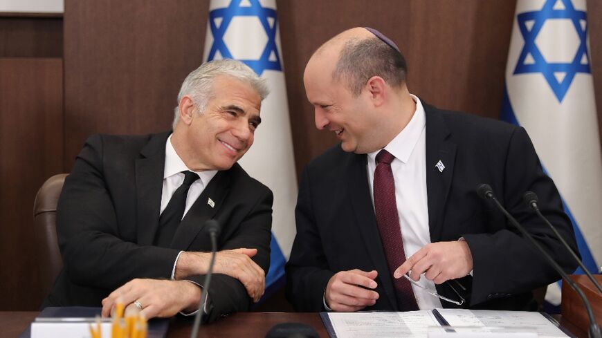 Israeli Prime Minister Naftali Bennett (R) speaks with Foreign Minister Yair Lapid (L) during a cabinet meeting in Jerusalem, 