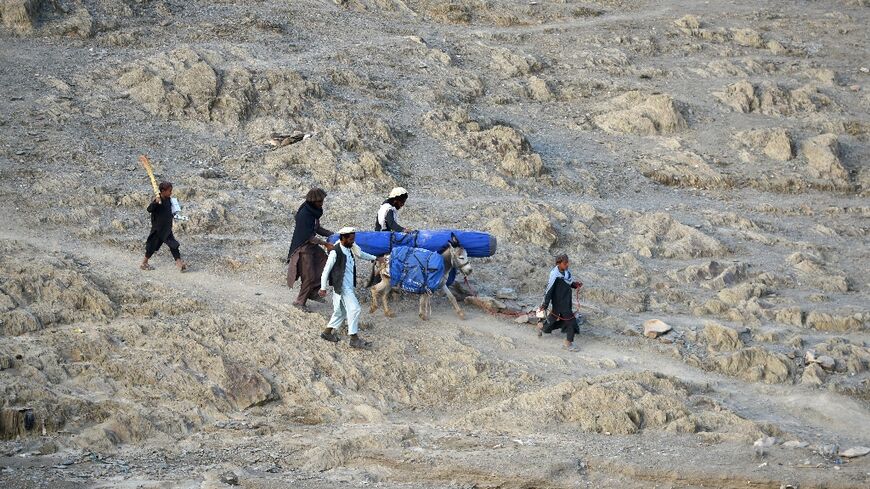 Volunteers carry aid from the International Organization for Migration for Afghans hit by a major earthquake in the Spera district in Khost province