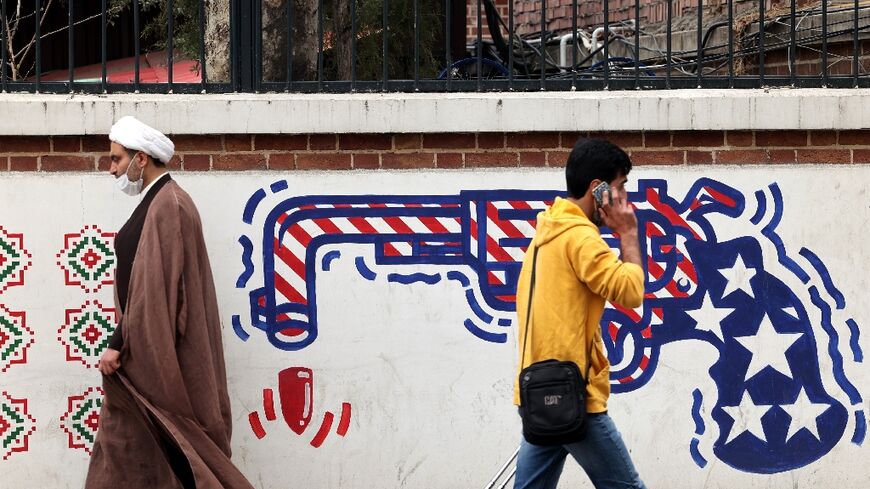 Iranians walk past an anti-US mural on a wall of the former United States embassy in the capital Tehran