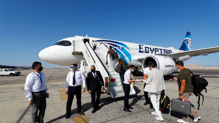 Mask-clad EgyptAir crew check the documents of travelers preparing to board an Airbus A320neo aircraft on the tarmac at Sharm el-Sheikh International Airport, Sinai Peninsula, Egypt, June 20, 2020.