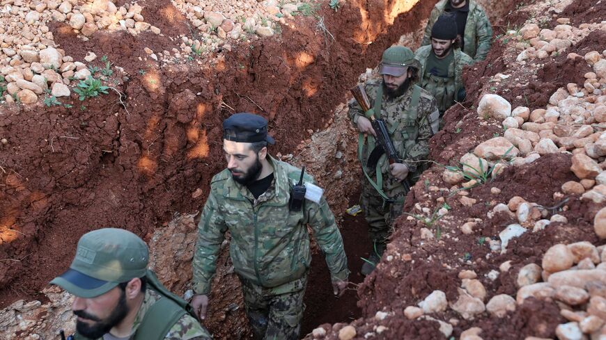 Syrian rebel fighters for the National Liberation Front advance in a trench.